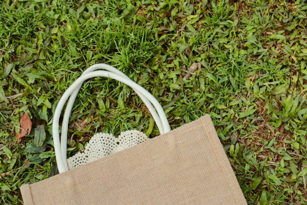 a brown bag sitting on top of a lush green field, green tardemarks, green tags