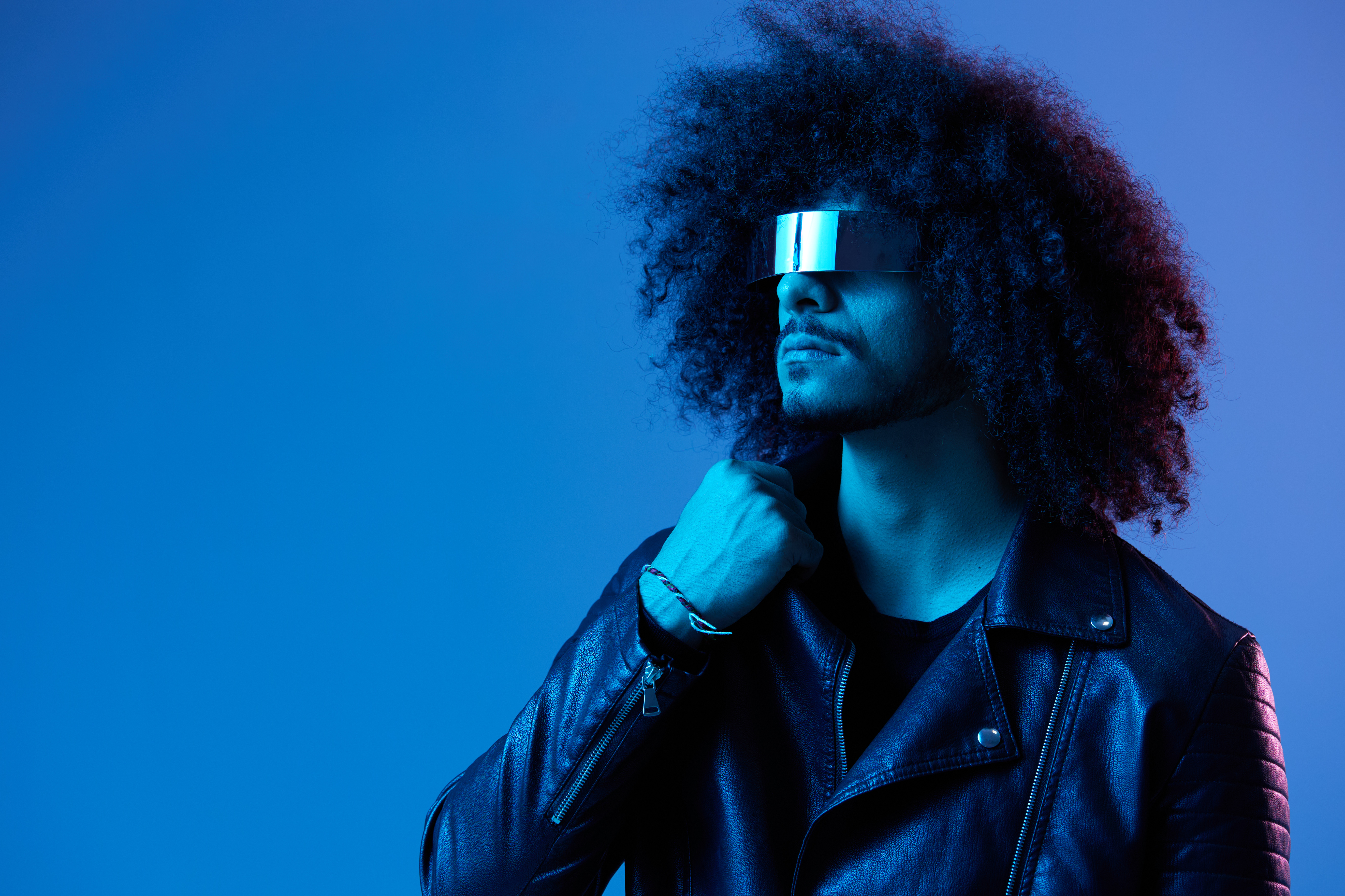 Portrait of fashion man with curly hair with stylish glasses on blue background multinational