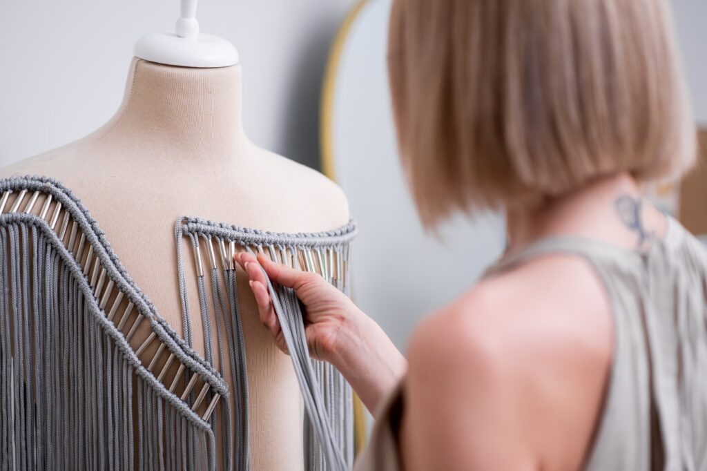 Designer checks stylish macrame decorative element for dress in fashion atelier outfit trend