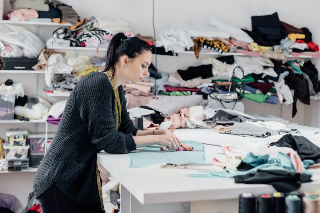 Fashionable business seamstress, portrait of happy woman tailor workplace sews.