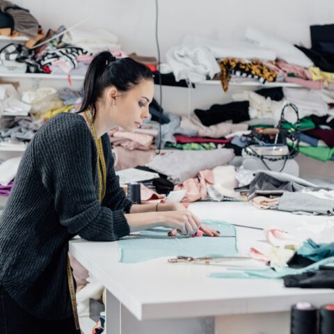Fashionable business seamstress, portrait of happy woman tailor workplace sews.