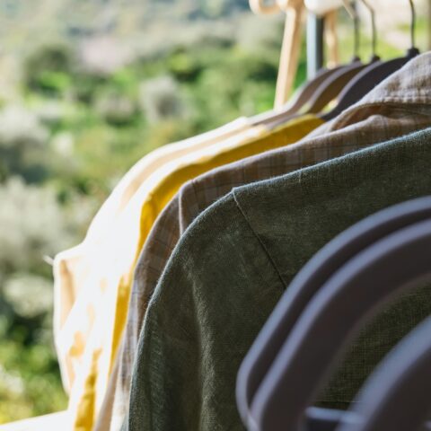 Linen clothes on gray hangers on the clothes rack. Slow Fashion. Sustainable seasonal Sale concept.