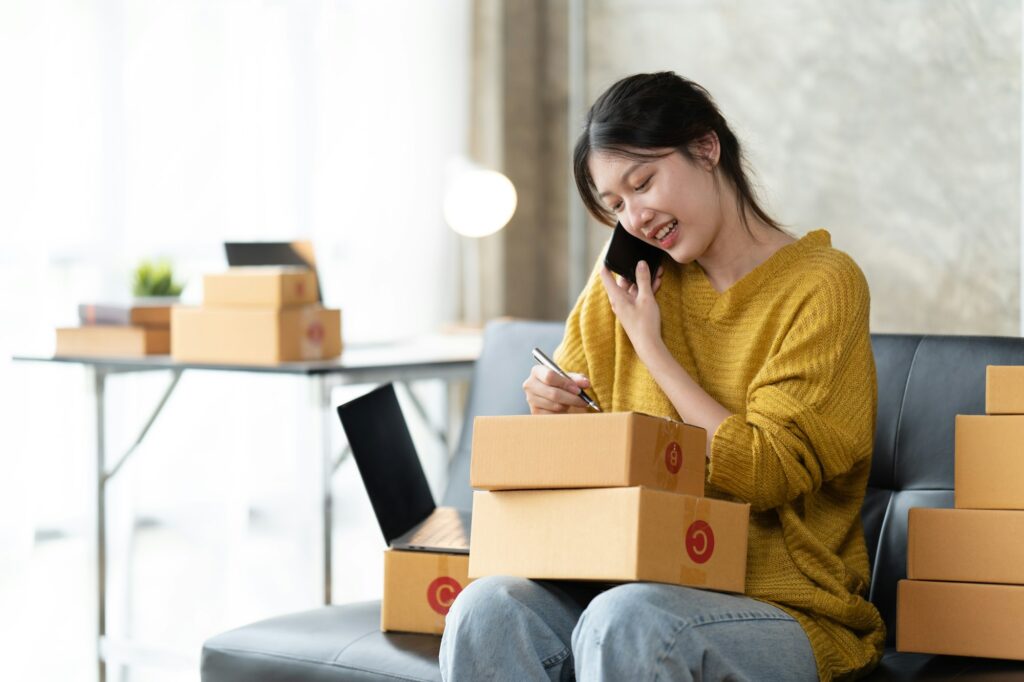 Asian woman business owner works with a box at home, prepare parcel delivery SME supply chain.