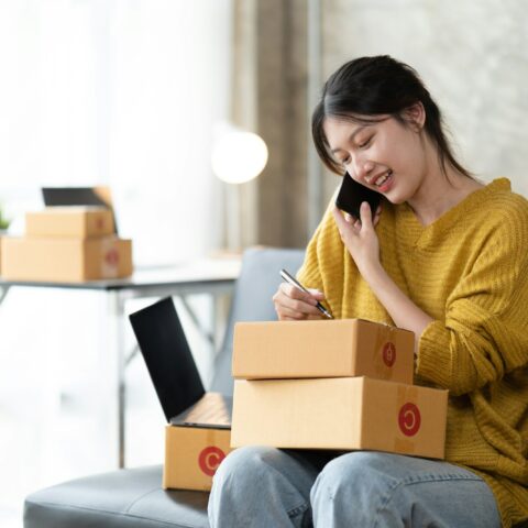 Asian woman business owner works with a box at home, prepare parcel delivery SME supply chain.