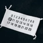 Maison Margiela’s iconic white label with four stitches symbolizing anonymity