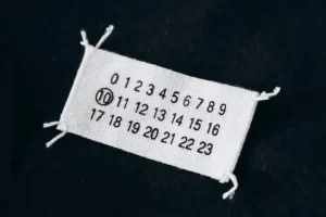 Maison Margiela’s iconic white label with four stitches symbolizing anonymity
