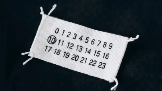 Maison Margiela’s iconic white label with four stitches symbolizing anonymity