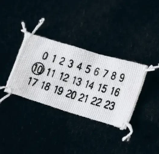 Maison Margiela’s iconic white label with four stitches symbolizing anonymity
