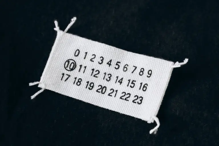 Maison Margiela’s iconic white label with four stitches symbolizing anonymity