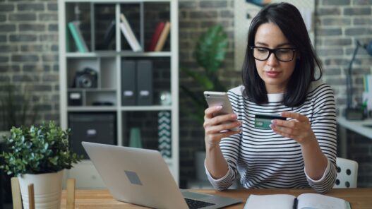 a woman sitting at a table looking at her cell phone, discount calculate