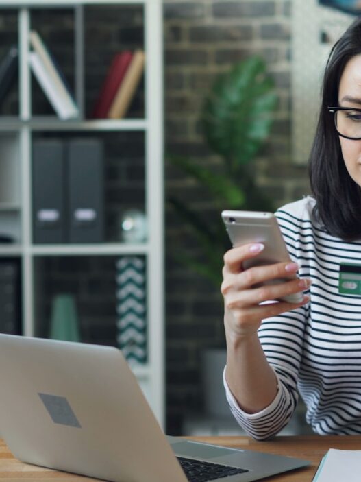 a woman sitting at a table looking at her cell phone, discount calculate