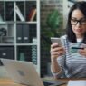 a woman sitting at a table looking at her cell phone, discount calculate