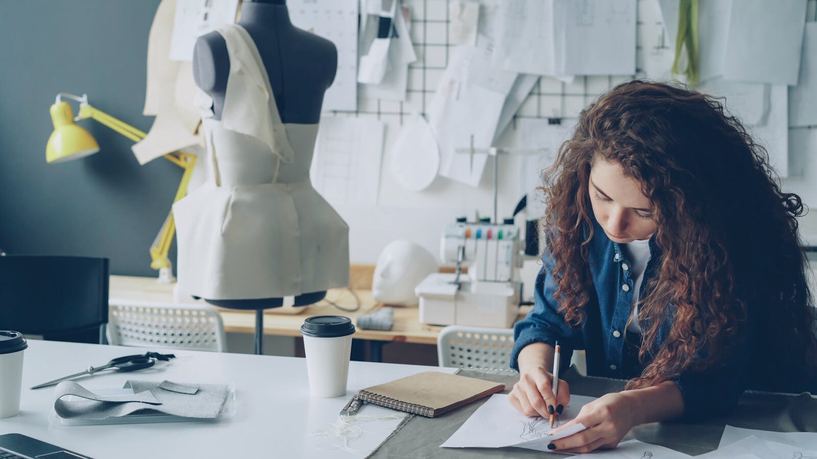 Young female fashion designer creating sketches in a modern studio.