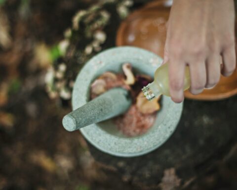 high angle photo of person pouring liquid from bottle inside mortar and pestle
