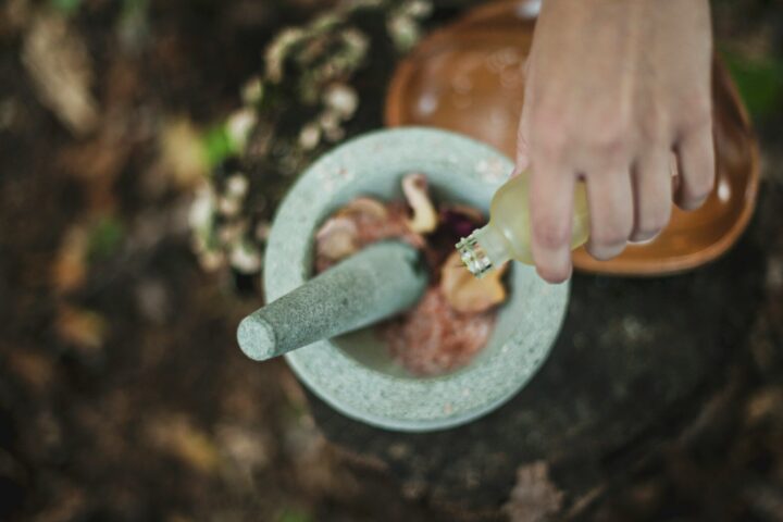 high angle photo of person pouring liquid from bottle inside mortar and pestle