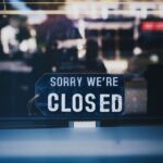 Moody image capturing a 'Sorry We're Closed' sign in a London shop window.