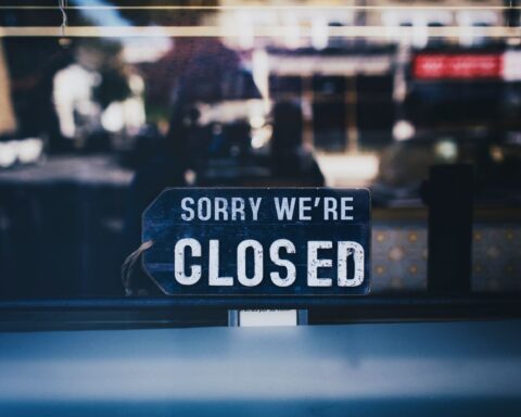 Moody image capturing a 'Sorry We're Closed' sign in a London shop window.