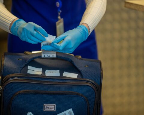 Close-up of airport security process with gloved hands inspecting luggage tags.