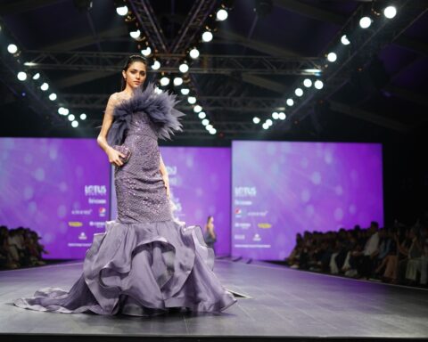 A model in a stunning purple gown walks the runway at a prestigious fashion event.