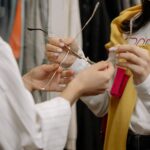 Two women trying on sunglasses in a stylish fashion boutique. Focus on hands and eyewear.