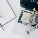 Creative depiction of online shopping with a miniature cart on a laptop keyboard.