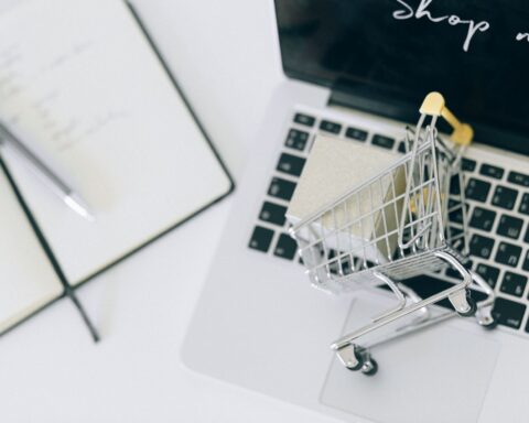 Creative depiction of online shopping with a miniature cart on a laptop keyboard.