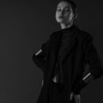 Sophisticated portrait of a woman with short hair posing elegantly in a monochrome studio setting.