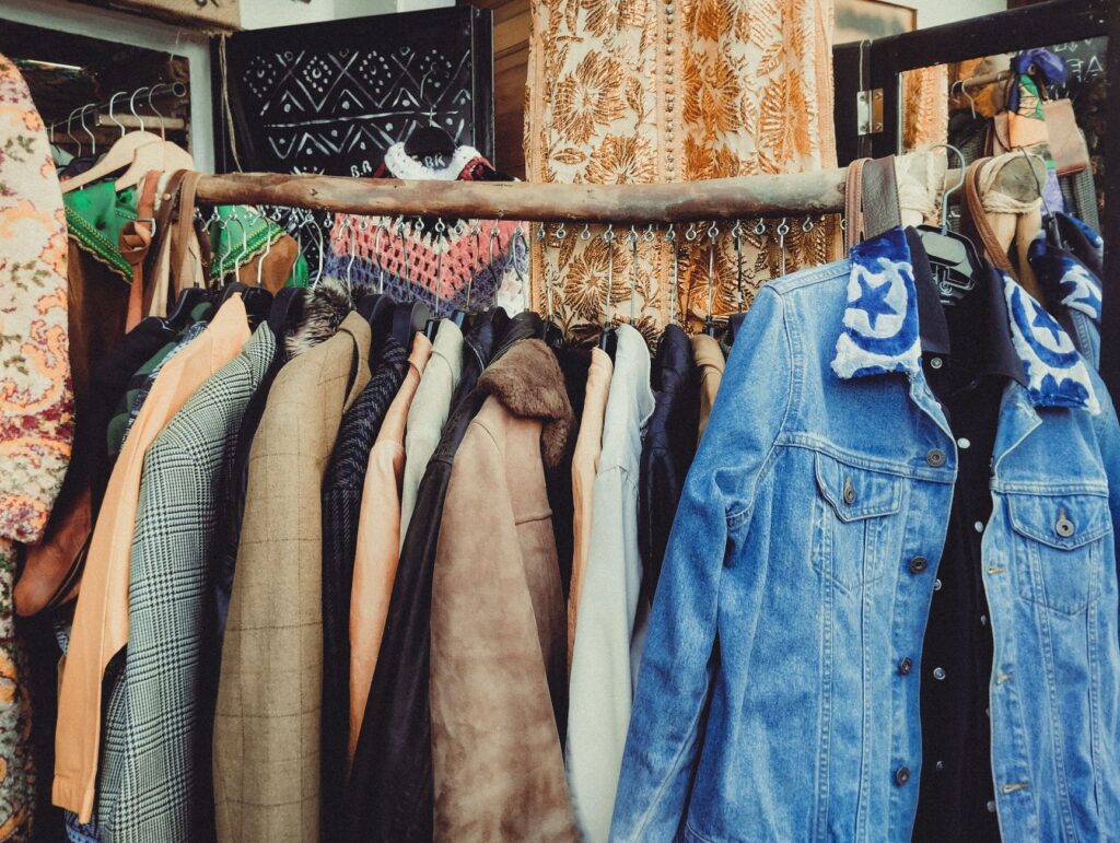 A vibrant assortment of vintage jackets hanging on a wooden rack in a boutique.