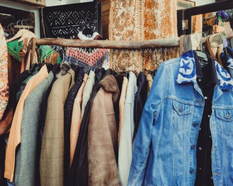 A vibrant assortment of vintage jackets hanging on a wooden rack in a boutique.