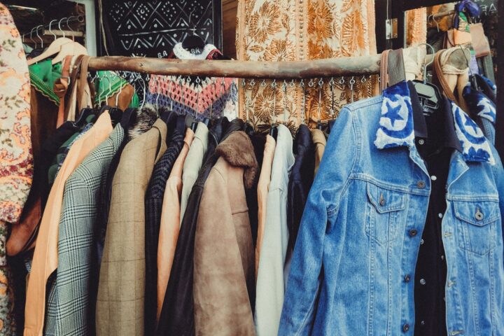 A vibrant assortment of vintage jackets hanging on a wooden rack in a boutique.