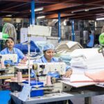 Garment workers sewing in a textile factory, illustrating fashion supply chain compliance