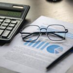 A financial document with a calculator, pen and glasses, illustrating lawyer salary data