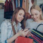 Two women shop and look at a phone.