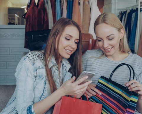 Two women shop and look at a phone.