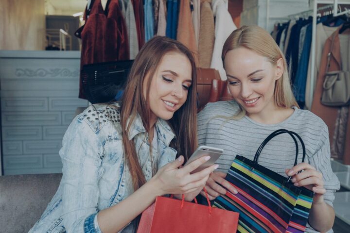 Two women shop and look at a phone.