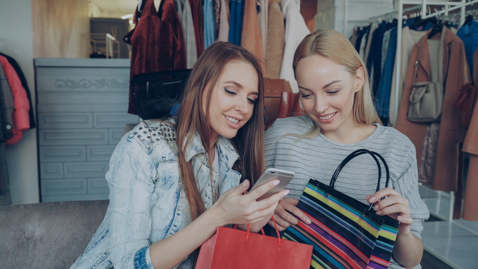 Two women shop and look at a phone.