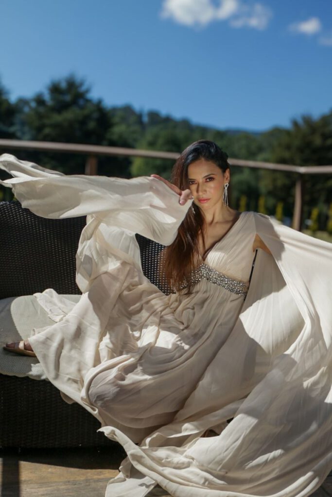 Portrait of a woman in a flowing white dress, exuding elegance and grace outdoors.