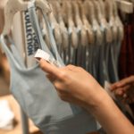 A shopper inspects a tag on a sports bra, highlighting retail shopping experience.