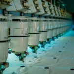 Row of industrial sewing machines in a garment factory, where a tech pack is used to make clothing