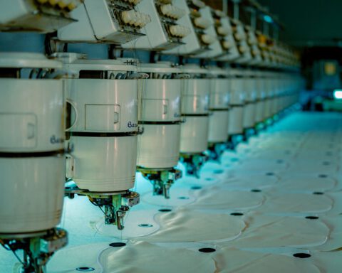 Row of industrial sewing machines in a garment factory, where a tech pack is used to make clothing