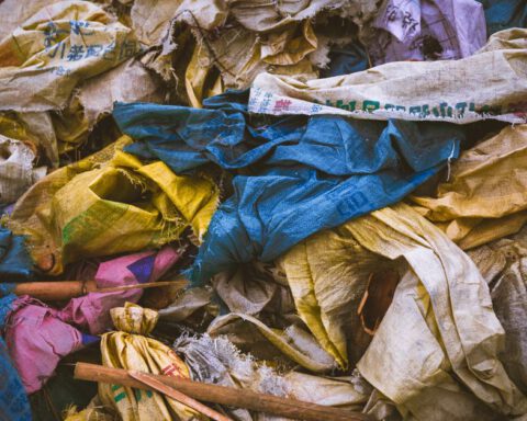 A vibrant mix of discarded textile bags in a recycling pile, showcasing the importance of waste management.
