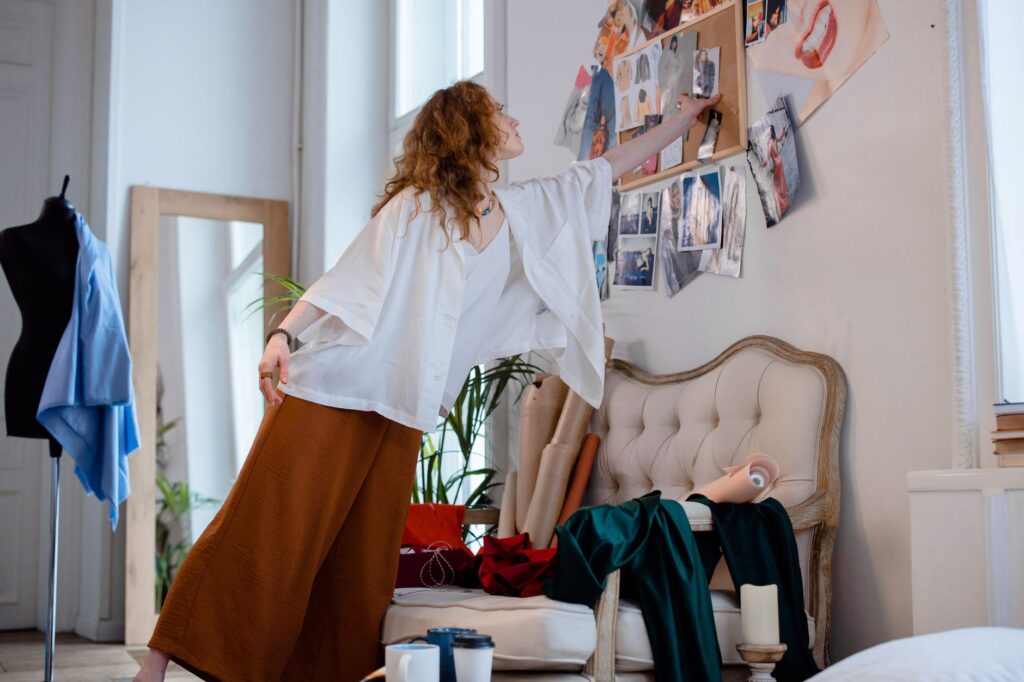 A fashion designer organizing sketches and materials in a stylish studio environment, enhancing a creative atmosphere.