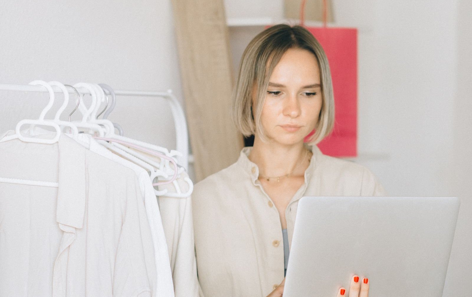 Fashion brand owner checking a laptop beside a rack of white shirts, illustrating Amazon Brand Registry enrolment