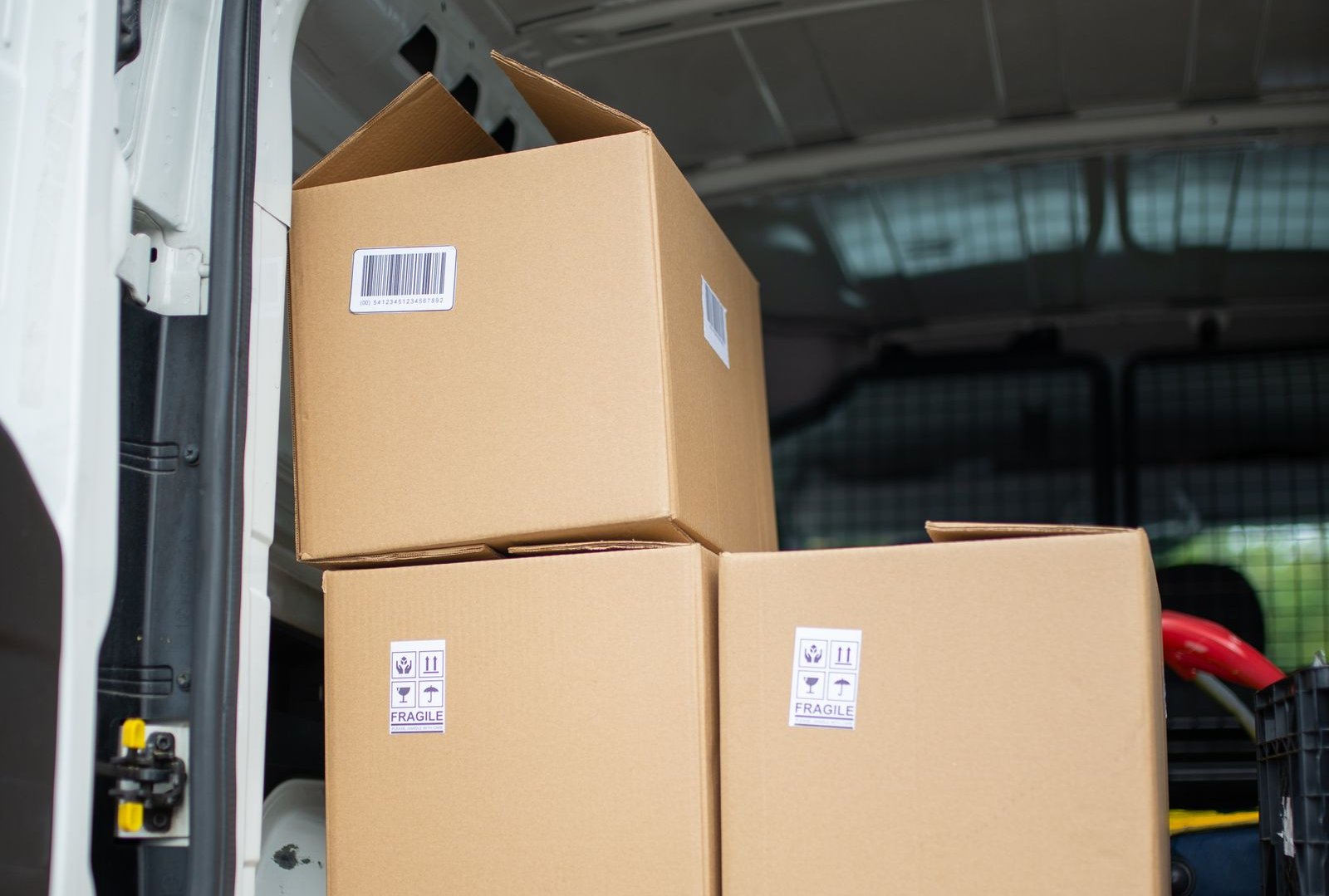 Plain cardboard parcels marked fragile stacked in the back of a delivery van, representing marketplace orders