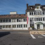 Audemars Piguet's historic manufacture building in Le Brassus with a clock and the company name on its white facade