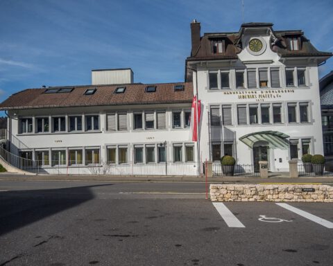 Audemars Piguet's historic manufacture building in Le Brassus with a clock and the company name on its white facade