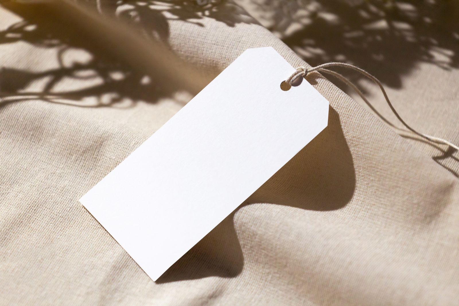 Blank white paper tag on linen fabric waiting for a clothing brand name