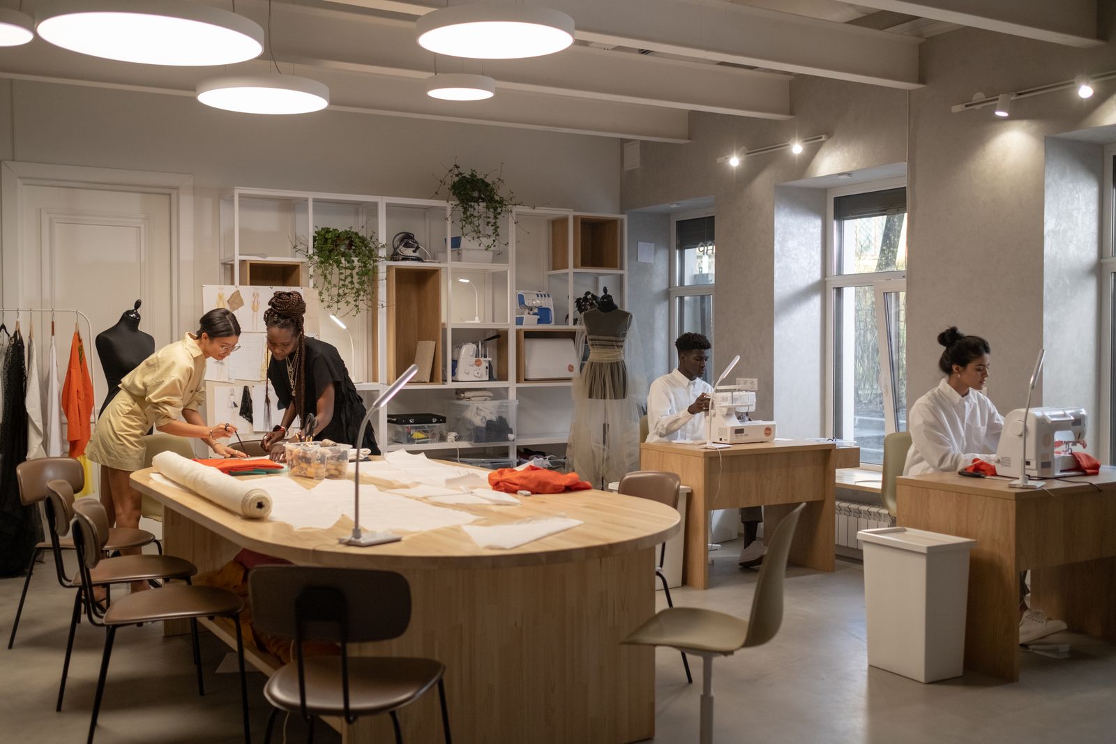 Young designers cutting patterns and sewing in a bright fashion studio, a typical setting for fashion internships
