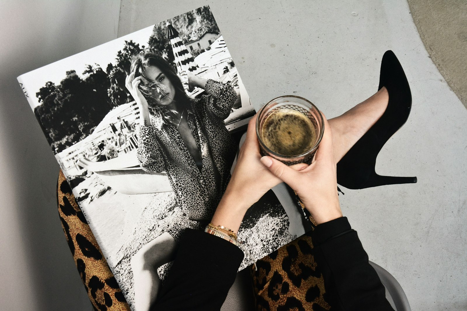 Black stiletto heels beside a magazine and coffee