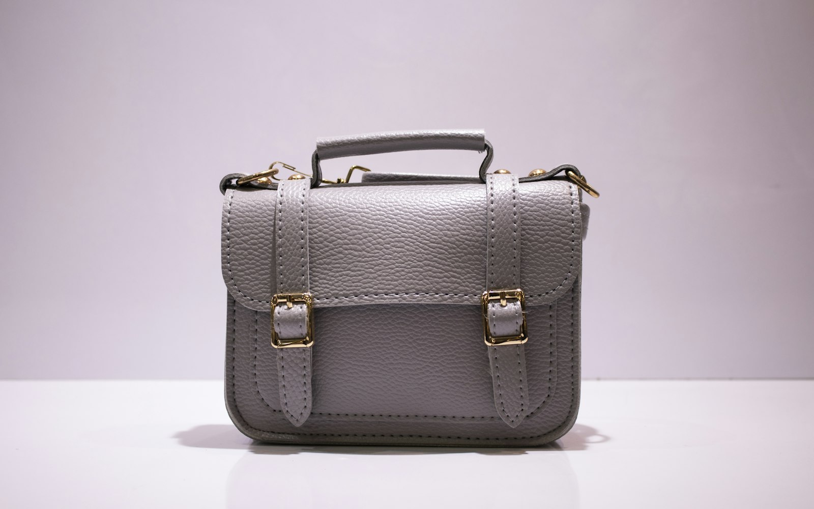 Grey leather satchel bag on a pink background
